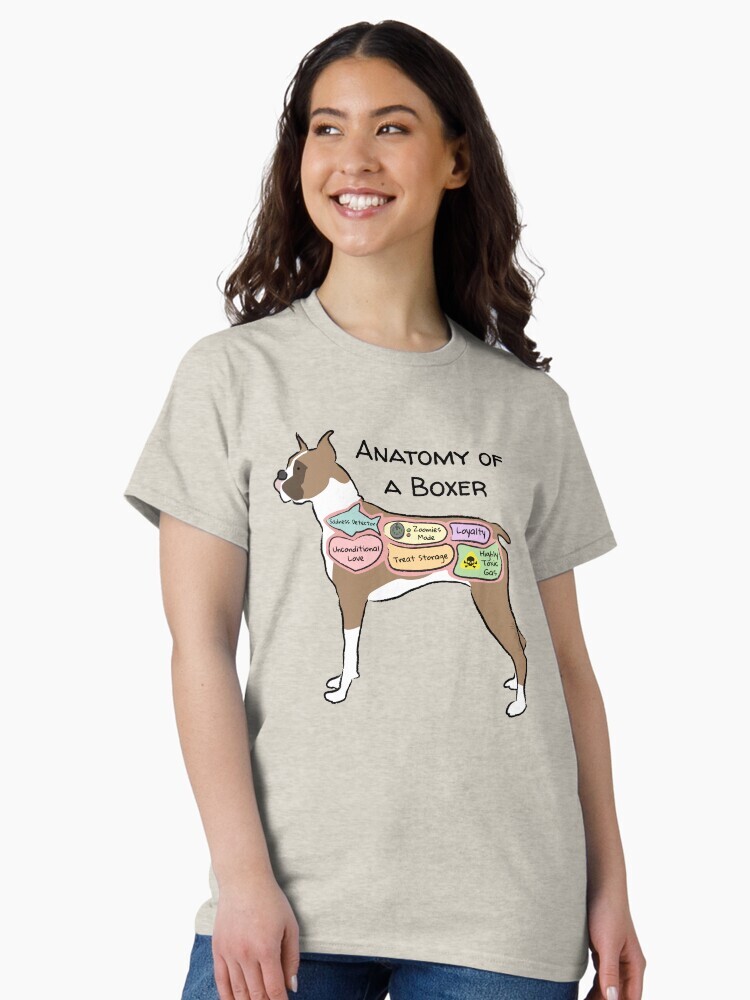 A brunette woman wearing a  t-shirt  featuring a cartoon illustration titled “Anatomy of a Boxer” showing a cute Boxer dog with funny labeled anatomy sections.