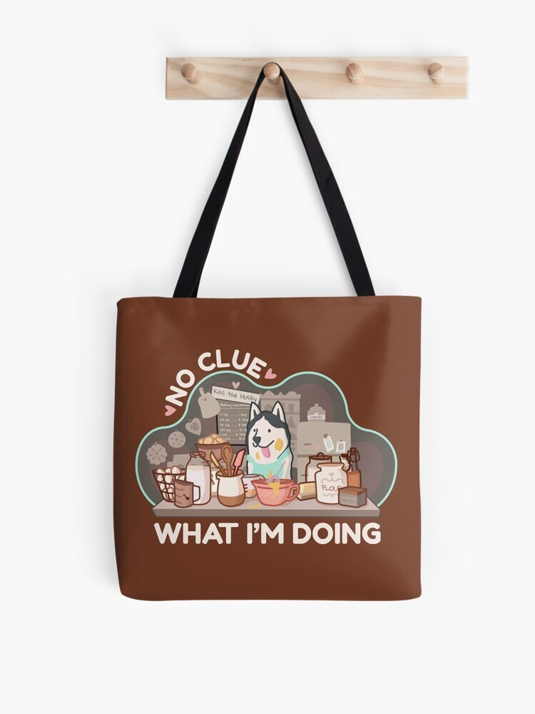 A brown tote bag hanging off a wooden hook. On the tote bag features a cartoon illustration with text saying 